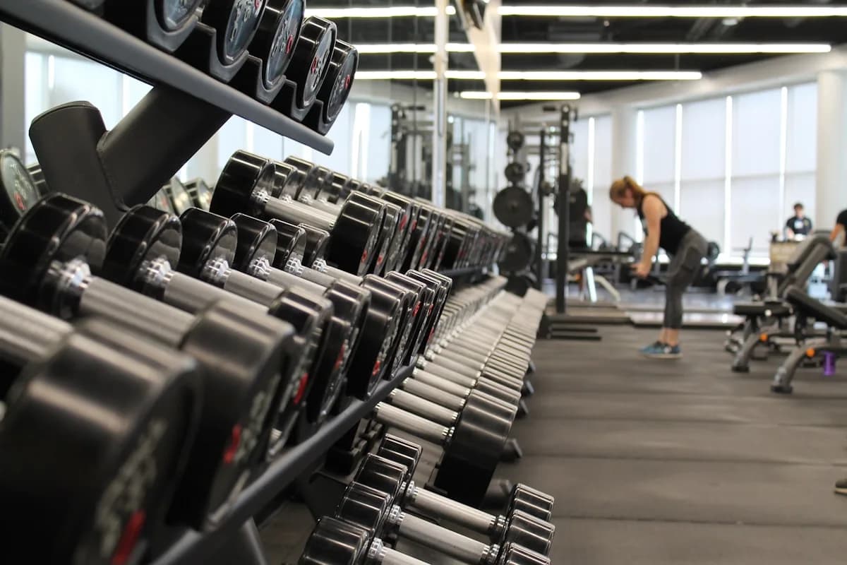 Man and woman in red sportswear lifting dumbbells during a workout in a bright gym, representing fitness franchise opportunities in the UK.