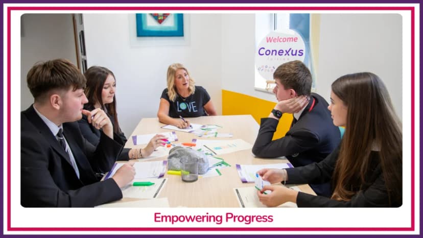 A Conexus Tuition tutor leading a small-group session with four secondary-age students around a table beneath a 'Welcome to Conexus' wall display, captioned 'Empowering Progress'